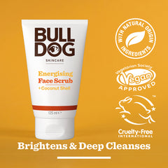 A tube of Energising Face Scrub stands on an orange background. Text highlights natural origin ingredients, vegan approval, and cruelty-free status. Brightens & Deep Cleanses is written below this exfoliator.
