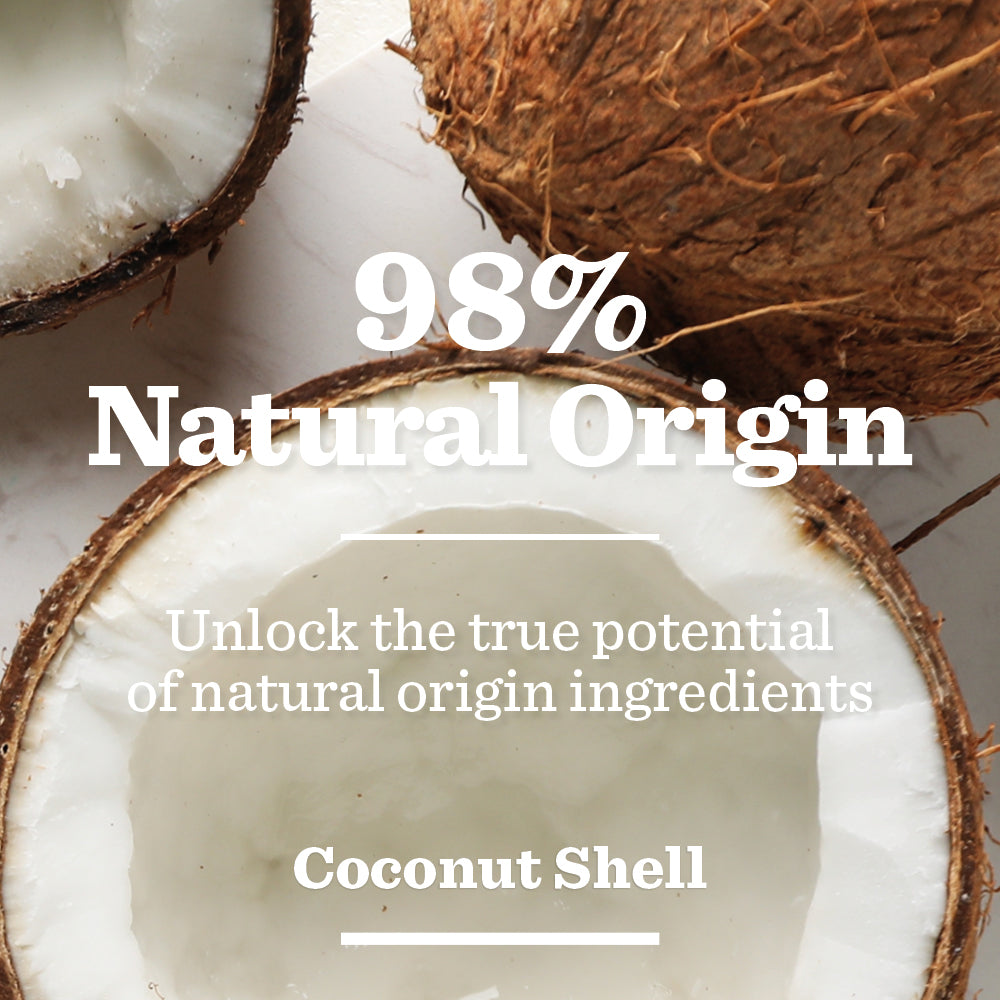 Three halved coconuts with white flesh and brown shells are shown on a light surface. Text reads: “98% Natural Origin. Energising Face Scrub exfoliates with Coconut Shell to unlock the true potential of natural ingredients.”.