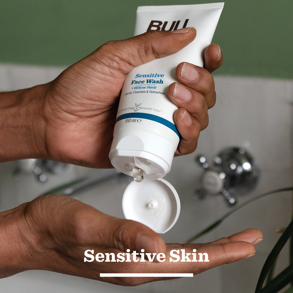 A person sprays Sensitive Spray Deodorant Bundle onto their underarm over a bathroom sink, with the words Sensitive Skin shown at the bottom of the image.