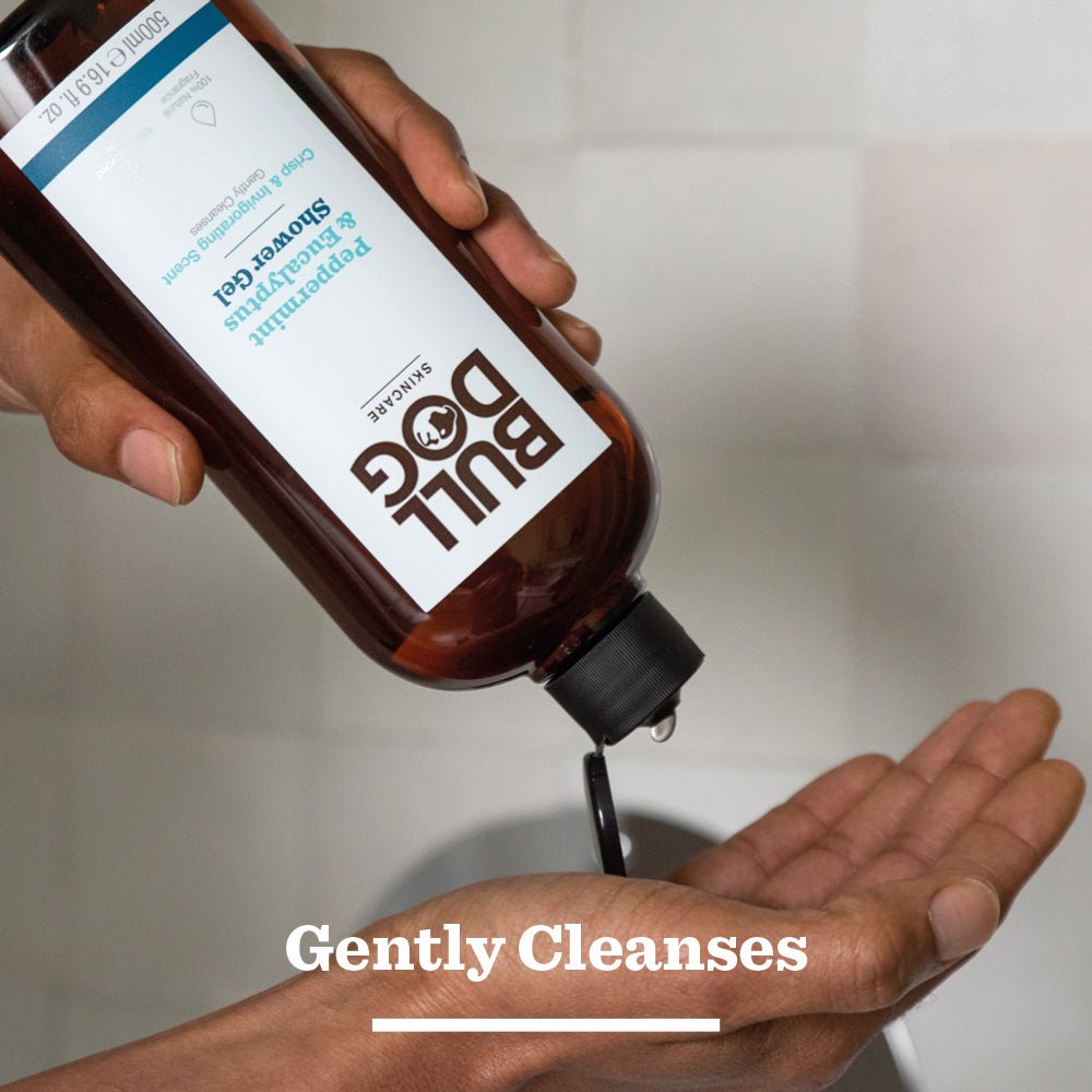 A person pours Peppermint & Eucalyptus Shower Gel, prized for its invigorating cleanse and natural fragrance, from a brown bottle onto their palm. The words “Gently Cleanses” appear at the bottom of the image.